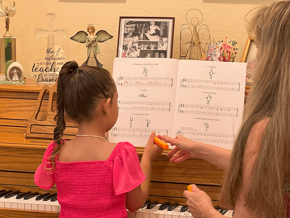 Mrs. Robin handing her student a highlighter at the piano.